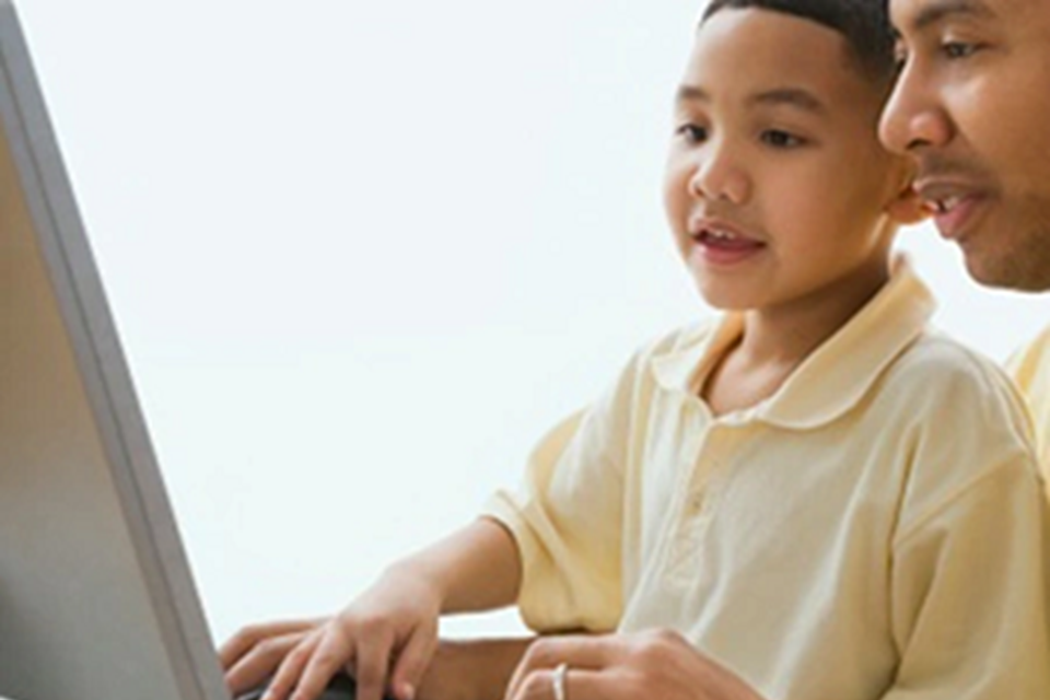 Photo of man and child viewing computer screen